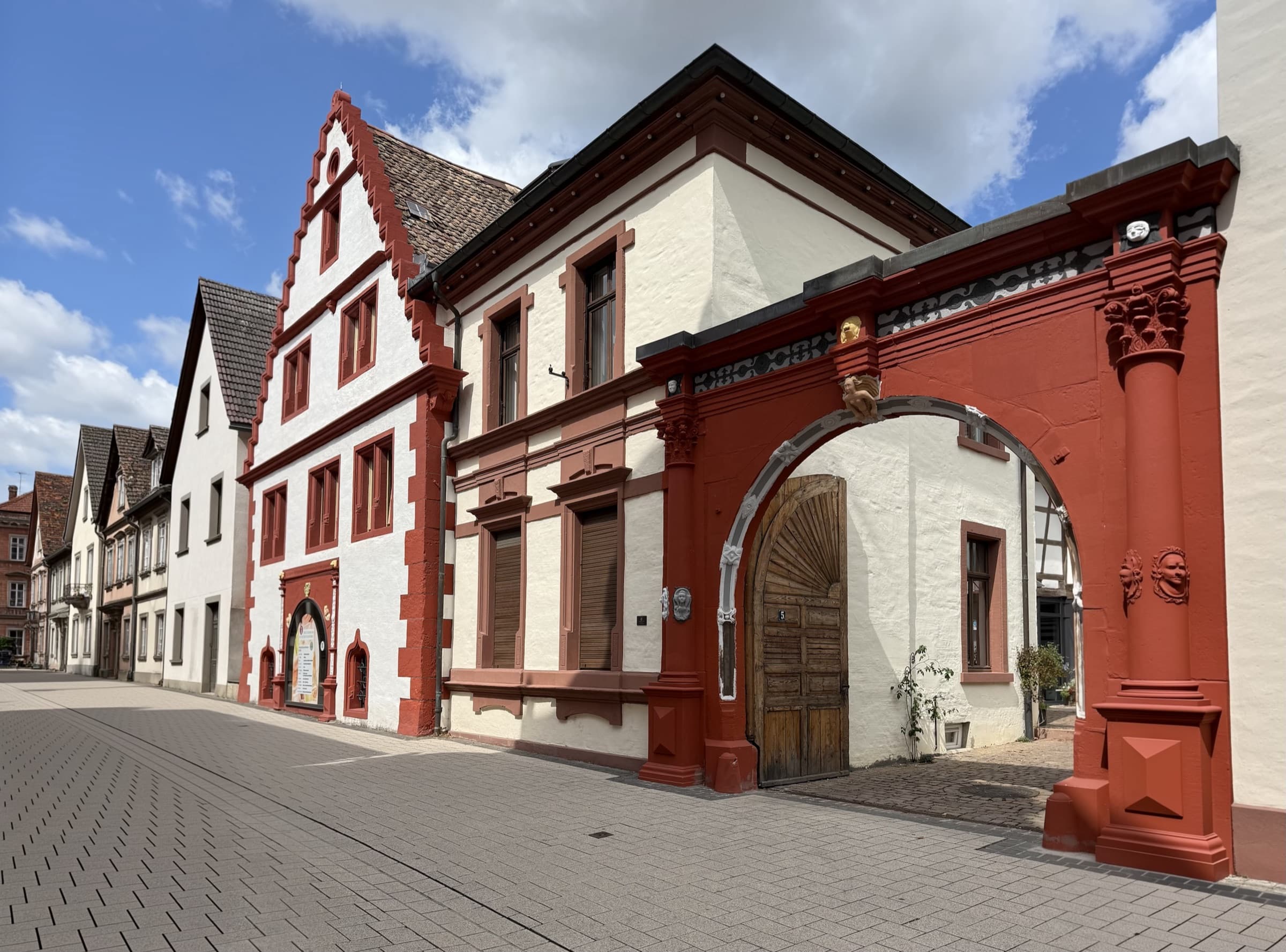 Historische Weindorf-Häuser mit rotem Sandsteinportal und Treppengiebel unter blauem Himmel