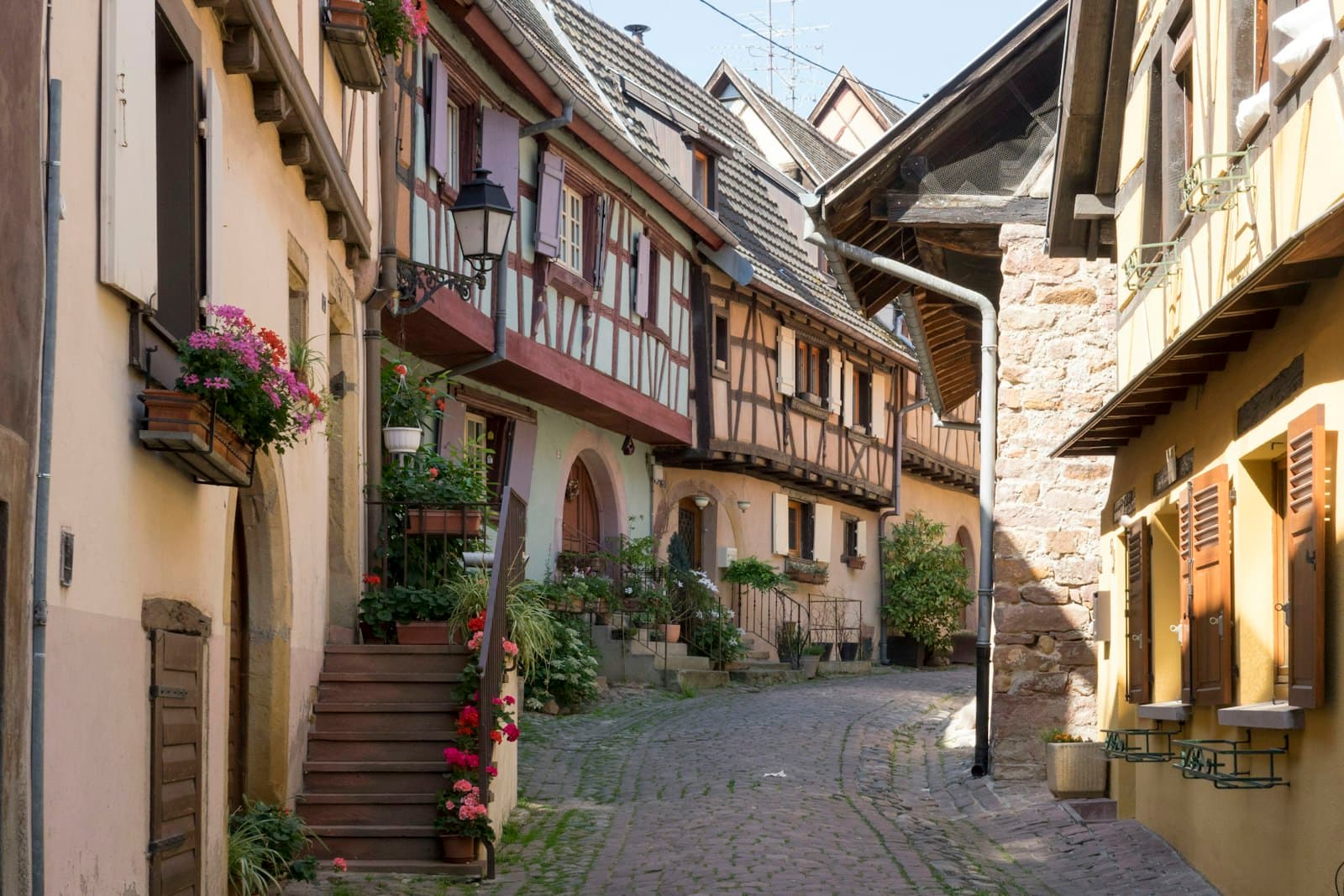 Enge Kopfsteinpflastergasse mit Fachwerkhäusern und Blumenkästen