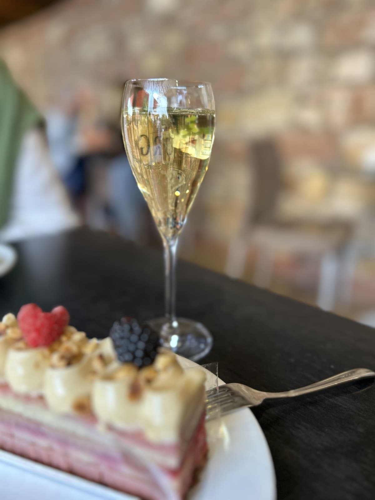 Glas Sekt und ein Stück Torte mit Beeren auf einem Cafétisch